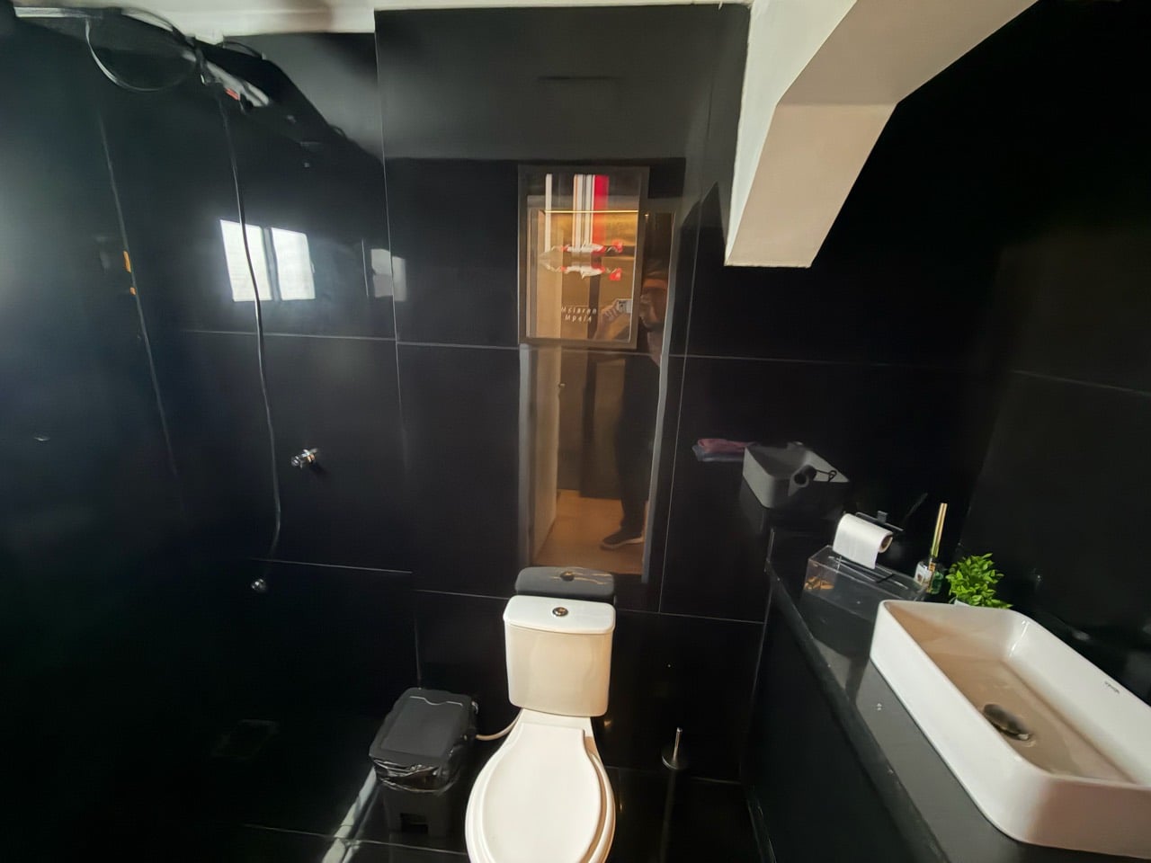 Banheiro com revestimento escuro, pia e vaso sanitário