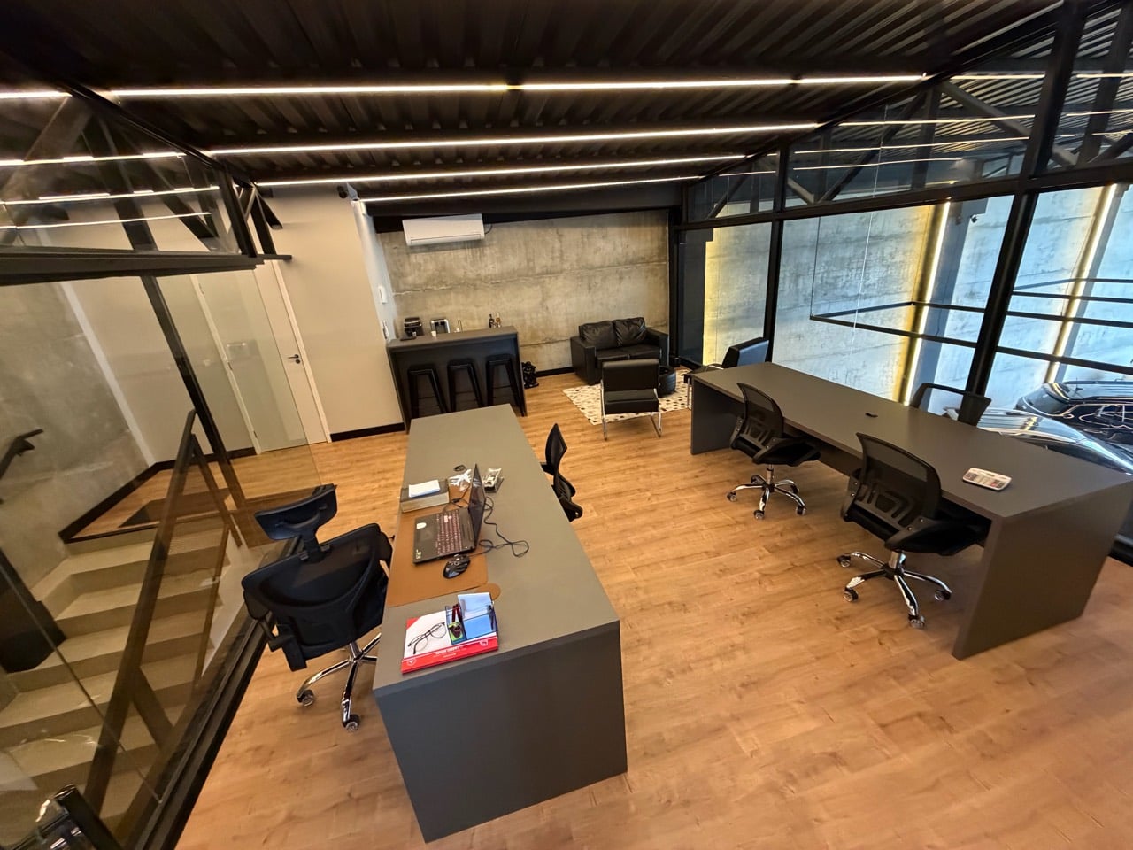 Visão geral do mezanino com mesas de trabalho, escada, copa e estar